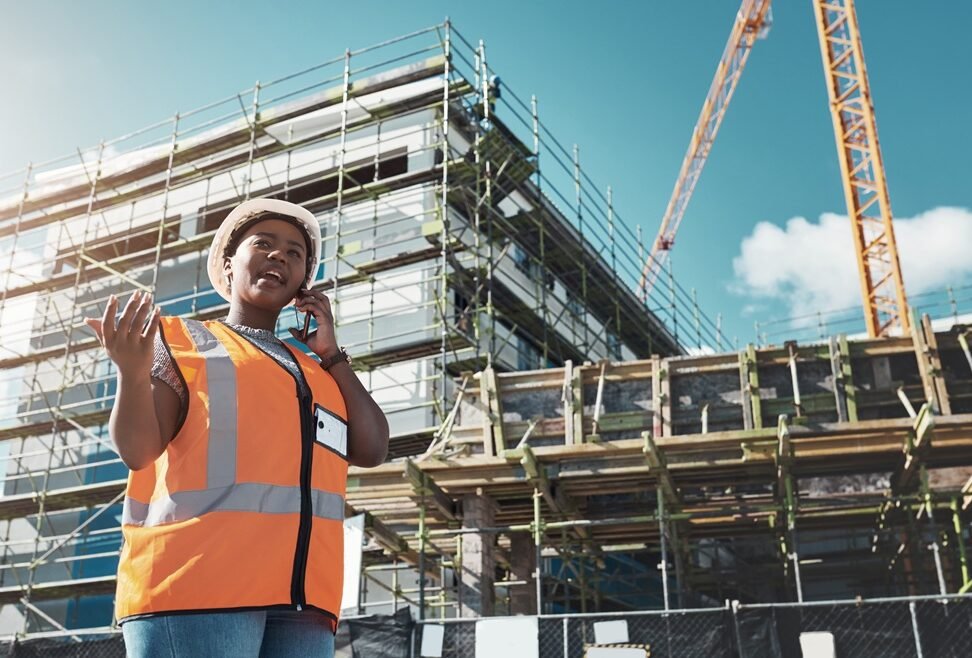 Shot of a young woman using a smartphone while working at a construction site.
